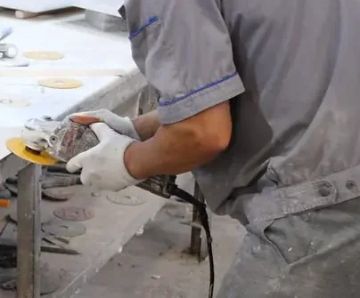 Worker hand-finishing a stone edge with a polishing tool